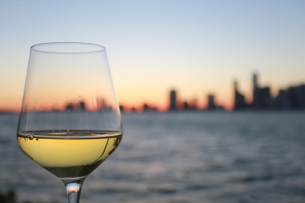 Glass of Chardonnay White Wine Overlooking the City of Miami Skyline Blurred After Dusk at Twilight in Key Biscayne, Florida